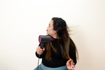Woman drying long hair with a modern hairdryer, wind effect