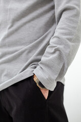 Side view of man in grey t-shirt with hand in pocket of black pants