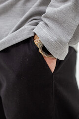 Close-up of mans hand in pocket of black pants with smartwatch under grey t-shirt