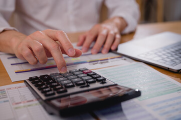 Businessman hand using calculator to budgeting and tax calculation monthly expenses. budget management and accounting on table. Business finance accounting banking concept.