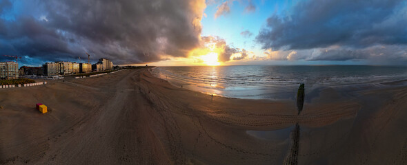 A breathtaking, stunning sunset scene at the beautiful beach, highlighting reflective water and moody, dramatic clouds