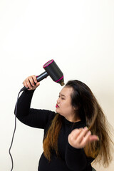Woman drying her long brown hair with a modern hairdryer