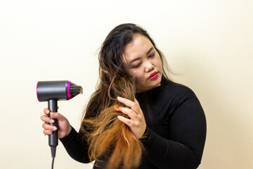Woman blow drying long messy brown hair with a modern hairdryer