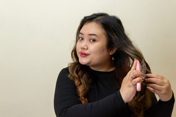 Young woman brushing long wavy hair, close-up portrait, beauty, self-care