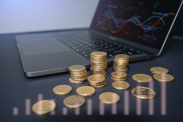 Investment and financial Taxation concept, gold coins with computer laptop with blurred chart for investment background