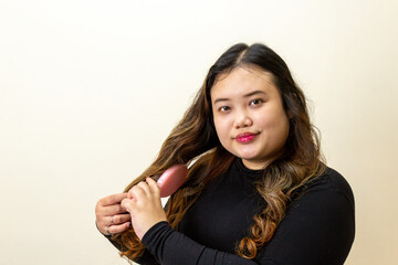 Young Woman Brushing Long Wavy Hair with Pink Brush, Beauty Routine