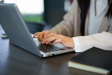 A Woman Working Outdoors, close up of hands typing on a laptop keyboard