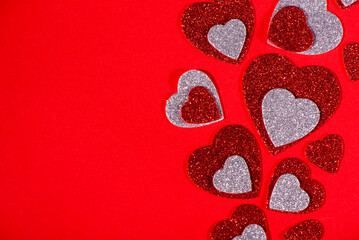 Red and Silver Glitter Hearts on Red Background with Copy Space. Romantic Valentines Day concept symbolizing love, affection, and celebration, with ample copy space for text or design.