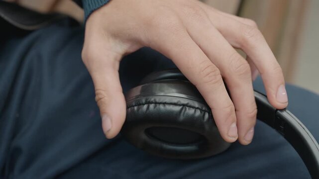 closeup hand adjusting headphone earcup, careful fingertips feeling worn cushion and scuffed leather sequence shows repair inspection by audio technician, musician tuning gear, commuter fidgeting
