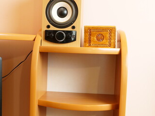 Wooden audio speaker with volume controls standing on shelf next to carved decorative box.