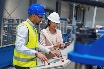 Female manager guides male worker on production process in busy factory. Focus on collaboration and workplace communication. © 24K-Production