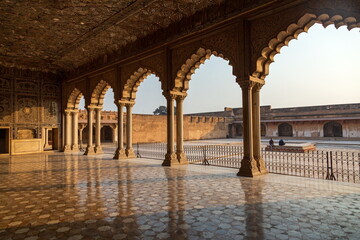 View of ornate arches framing a sun-drenched courtyard with reflective marble floors and ancient walls, a fusion of light and shadow, Lahore Fort, Punjab, Pakistan.