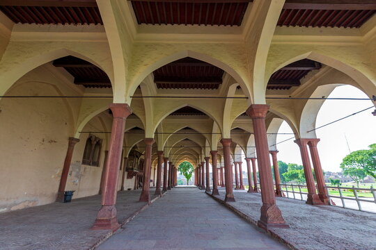 View of a long, symmetrical colonnade with red pillars and arches under a wooden ceiling stretches to the horizon, Lahore Fort, Punjab, Pakistan.
