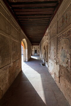 View of a long, shadowed corridor in the Lahore Fort, with textured walls and arched doorways creating a sense of depth and history, Lahore, Punjab, Pakistan.