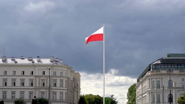 Breathtaking view of Polish National Flag Waving in Wind Against Moody Sky and Classical Architecture