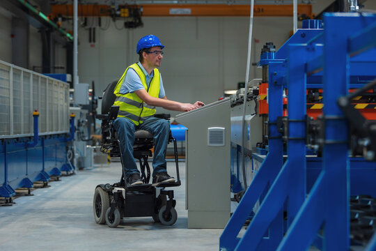 Worker with disability using wheelchair operates an industrial machine in a factory setting focused on inclusive employment and safety.