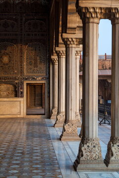 View of intricately carved pillars stand in stately formation, casting shadows on the patterned floor, a testament to time and artistry, Lahore, Punjab, Pakistan.