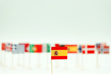 Flags from different countries displayed on small sticks with a focus on the Spanish flag in the foreground during a cultural event
