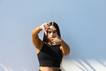 Young person in casual clothes smiling, making a frame with their hands and fingers, with a happy face. The concept of creativity and photography.