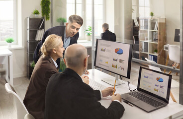 Businesswoman and businessman team meeting for analysis. Colleagues review data and charts on...