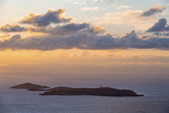 Nisos Gaidaros island with lighthouse in the sea at sunrise with dramatic clouds, Ermoupoli, Syros, Cyclades, Greece