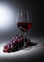 Ripe dark purple grapes paired with a clear stemmed glass full of rich red wine, suggesting harvest, vintage, and elegant tasting, healthy, dark, alcohol