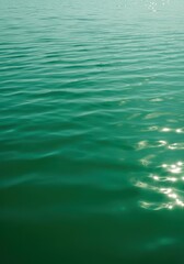 Obraz premium Abstract background texture of deep, vibrant lake water showing subtle ripples and reflecting the sunlight. The color is a rich emerald green, bright, wavy, environment
