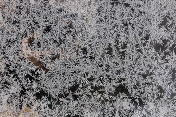 Frost forms intricate patterns on glass in the early morning light during winter