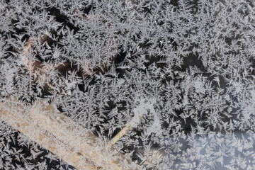 Frost forms intricate patterns on a window during a cold morning in winter