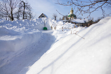 Snow path leads to a building with a dome during winter in a rural area with trees