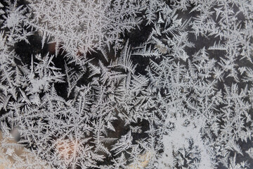 Frost patterns form on a window during cold winter morning in a rural area with trees in the background