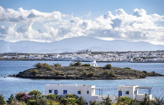 Small island with church Agia Kali, village view of Naoussa town and blue sea, white Cycladic houses and church Agios Faneromeni, Paros, Cyclades, Greece