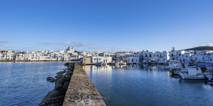 Local view of Naoussa town and blue sea, harbour with fishing boats, white Cycladic houses and church Agios Faneromeni, Paros, Cyclades, Greece