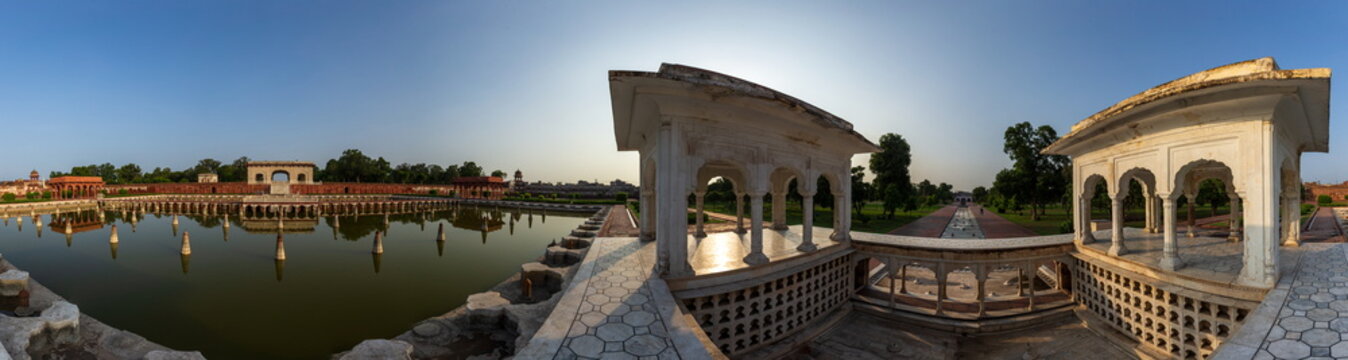 View of shimmering sunlight reflecting off a tranquil pool, framed by aged white structures, evoking a sense of serenity and timelessness, Lahore, Punjab, Pakistan.