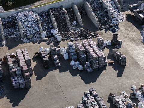 Aerial view of a recycling facility showing organized piles of scrap metal. Workers are sorting and managing different materials.