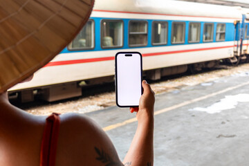 Tourist wearing non la viewing smartphone near train in Hanoi