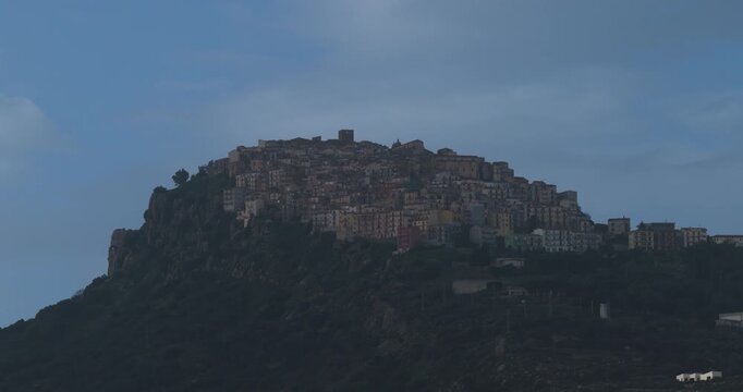 Aerial view of the settlement on a hill with buildings of various colors and sizes contrasting with the blue sky, Pollina, Sicilia, Italy.