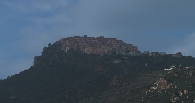 Aerial view of Pollina, a hilltop town where buildings cluster together, creating a captivating contrast against the dark green hillside, Pollina, Sicilia, Italy.