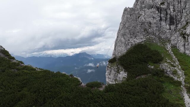 Adventurous person base jumping from a high alpine cliff