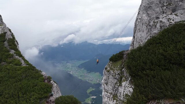 Aerial view of a highliner walking a slackline between mountain cliffs