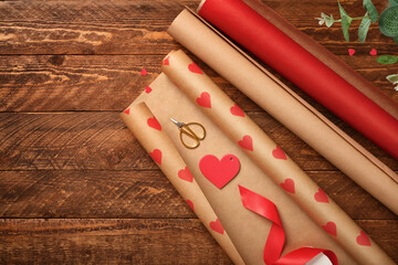 Gift wrapping background. Paper with red hearts, ribbon, and scissors on wooden background. Presents preparation. Copy space