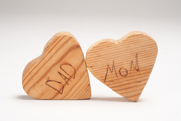 Small wooden Hearts Leaning Against Each Other That Say Mom and Dad Isolated on a White Background