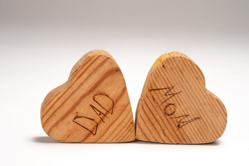 Small wooden Hearts that Say Mom and Dad Isolated on a White Background