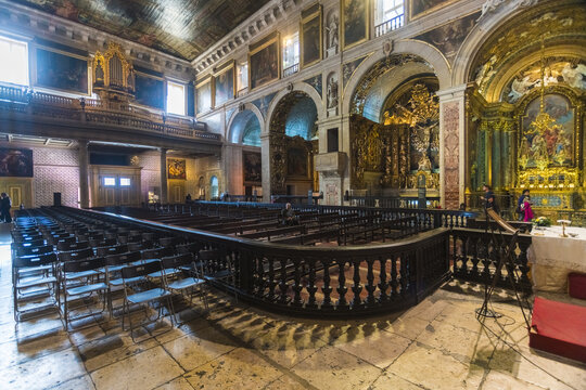 View of the grandeur of the Igreja de S&Atilde;&pound;o Roque, with its ornate gold carvings, dark wooden pews, and towering arches, bathed in a soft, reverent light, Lisbon, Lisbon, Portugal.