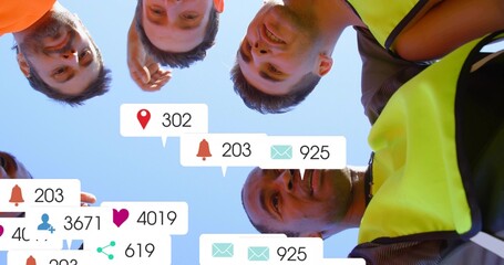 Huddling six men in hi-vis vest, leaning toward camera under clear blue sky with notification icons