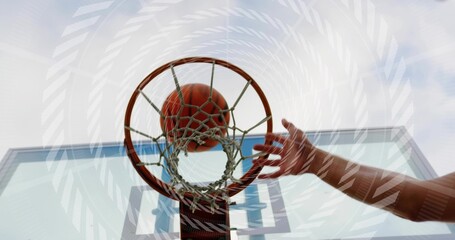Swooshing basketball passing through rim at outdoor court, bare arm reaching toward glass backboard