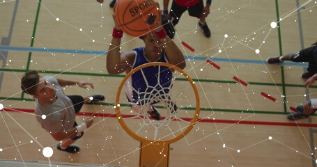 Jumping player in blue jersey reaching toward rim at gym, holding basketball above head