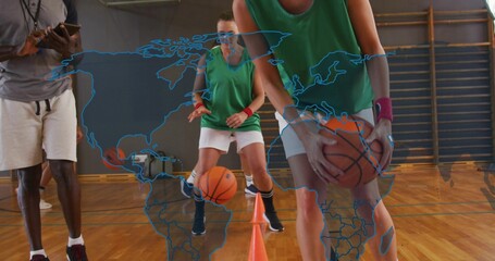 Holding basketball near orange cone, player in green jersey white shorts dribbling on gym court