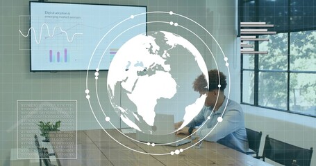 Working adult male wearing blue shirt on laptop at conference table, monitors, overlays, copy space