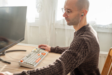 Programmer, young man in brown cable knit sweater working at computer, coding process, modern worker solving problems, specialist digital tasks, home office environment promoting productivity and calm